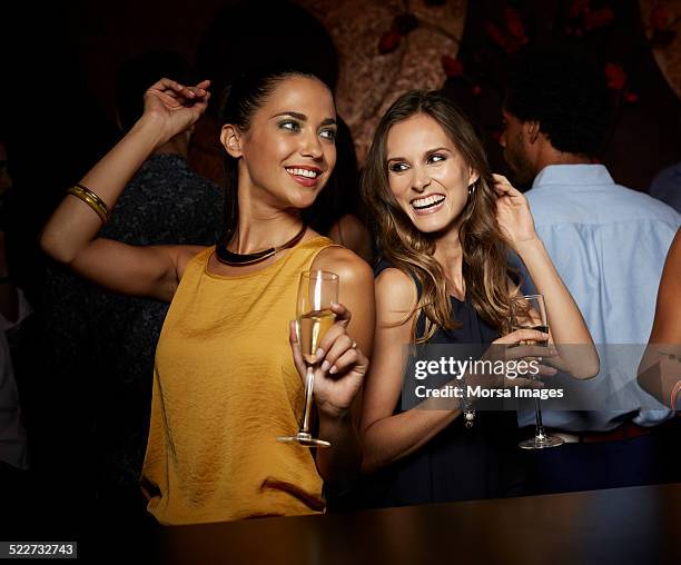 cheerful female friends dancing in nightclub - clubs fotografías e imágenes de stock