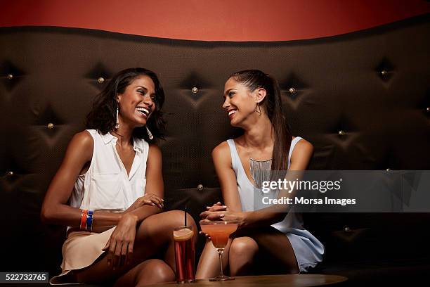 cheerful friends conversing on sofa in nightclub - night club lounge fotografías e imágenes de stock