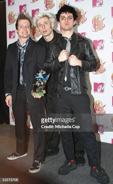 Mike Dirnt , Tre Cool and Billie Joe Armstrong of Green Day pose in the media room with the award for Best Group and Best Rock Video for "American...