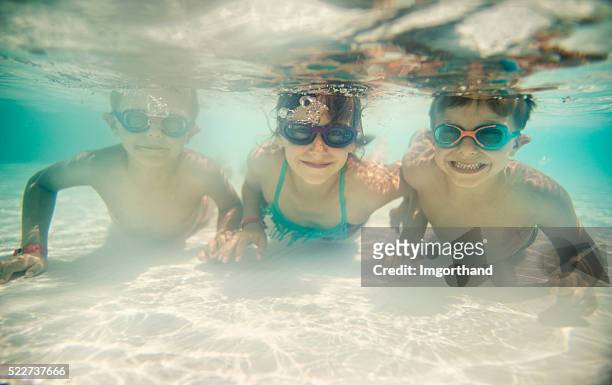 sister and brothers swimming underwater in shallow pool - shallow stock pictures, royalty-free photos & images