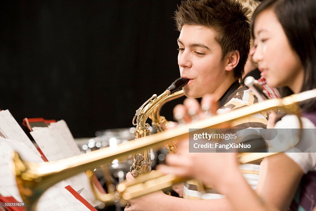 Teenage boy playing saxophone in high-school band