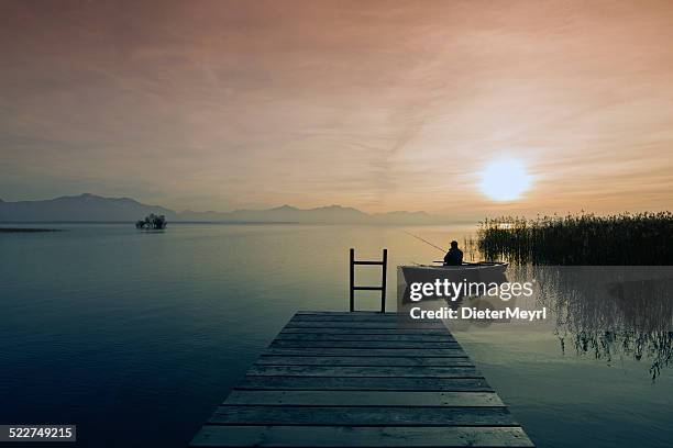 fisher in  boat at dusk - chiemsee stockfoto's en -beelden