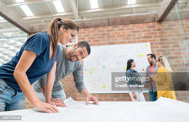 architects looking at blueprints at the office - redesign stock pictures, royalty-free photos & images