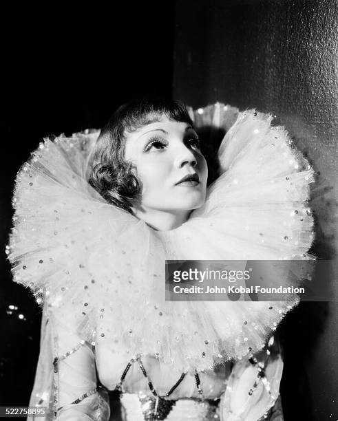 Portrait of actress Claudette Colbert wearing a ruff around her neck and a sequined costume, as she appears in the movie 'Tonight Is Ours', for...