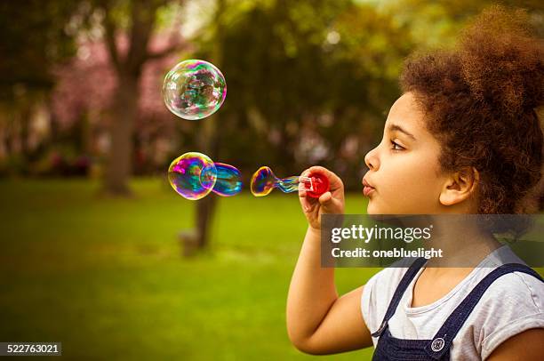 bambini (7-8) soffiare le bollicine nel parco giochi. - blowing bubbles foto e immagini stock