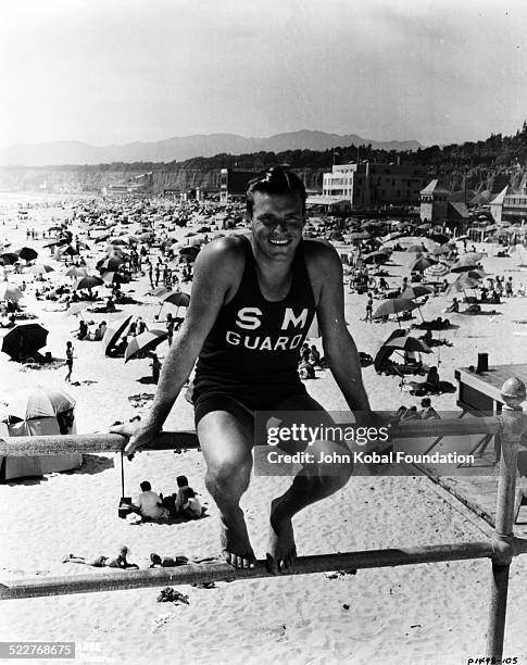 Portrait of actor and athlete Buster Crabbe , wearing a lifeguard uniform at the beach, for Paramount Pictures, 1933.