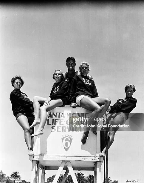 Portrait of actor and athlete Buster Crabbe , posing with women from the Santa Monica Lifeguard Service, for Paramount Pictures, 1933.