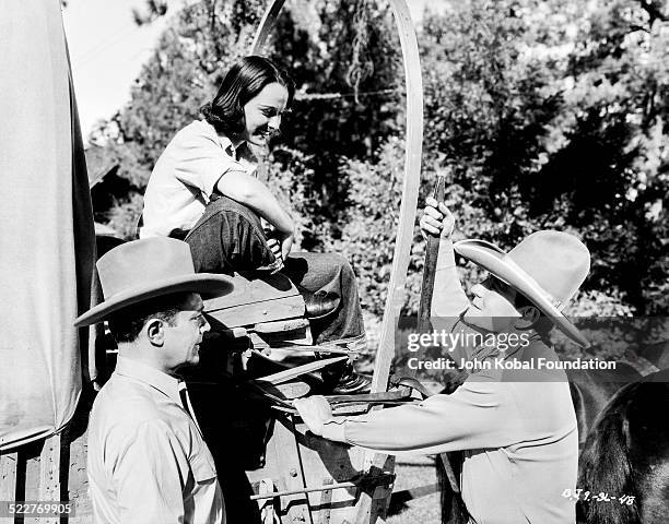 Actors Ray Corrigan , Louise Brooks and John Wayne on the set of the movie 'Overland Stage Raiders', for Republic Pictures, 1938.