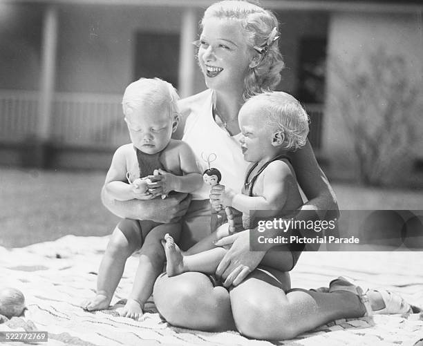 Actress Dixie Lee, wife of singer Bing Crosby, relaxing outdoors with their twin sons Dennis and Phillip, circa 1935.
