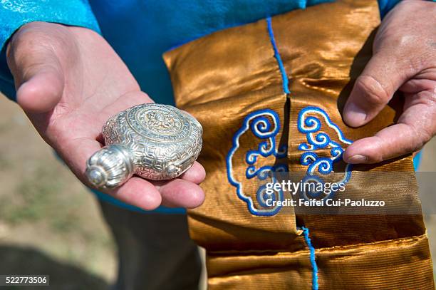 at tsetserleg, a man showing his silver snuff bottle, there is some powdered tobacco inside, it's for quotidian life and also  a decoration for traditional clothing, or for special day using. - nadaam festival stock pictures, royalty-free photos & images