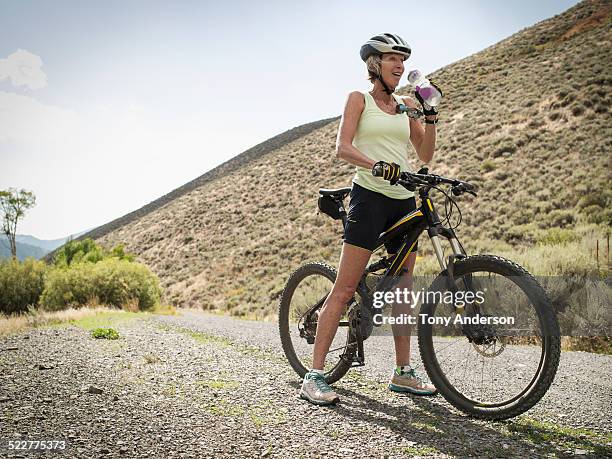 mature woman riding bike on mountain road - cycling shorts stock pictures, royalty-free photos & images