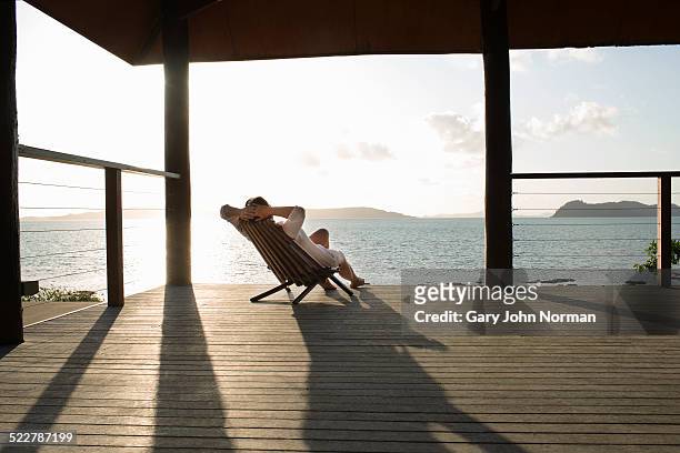 woman relaxing in deck chair on veranda. - ambientazione tranquilla foto e immagini stock