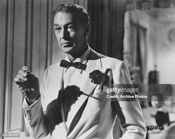 Portrait of actor Gary Cooper, wearing a tuxedo and a button hole, and smoking a cigarette, in a scene from the movie 'Love in the Afternoon', 1957.