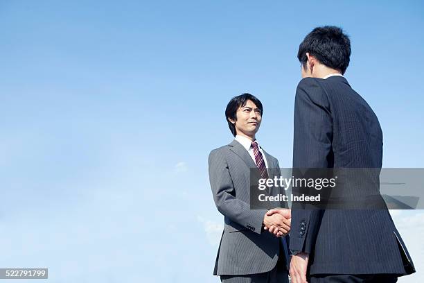 two men who shake hands - low angle view of two businessmen standing face to face outdoors stock pictures, royalty-free photos & images