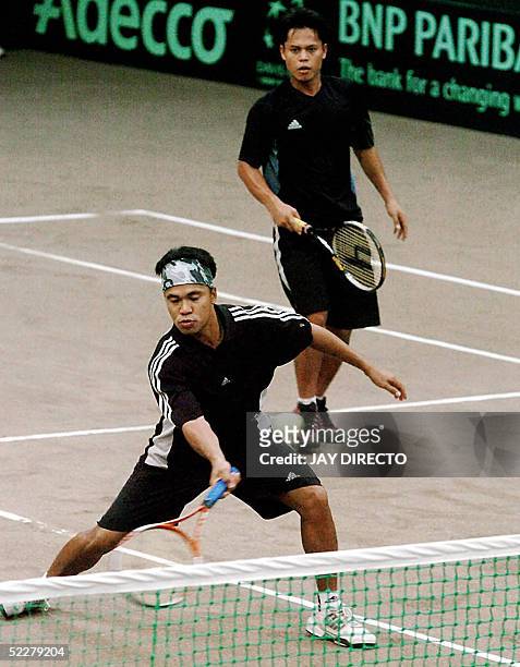 Philippines tennis player Rolando Roel hits a return while teammate Johnny Arcilla looks on during their doubles match against South Korea in the...