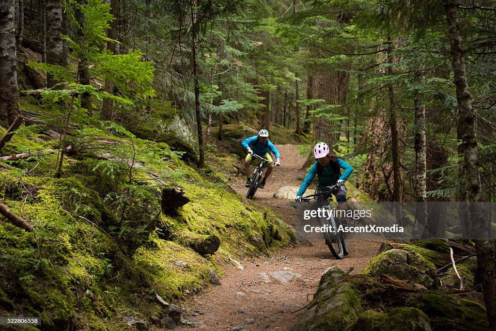 Couple, faire du vélo de montagne dans une forêt