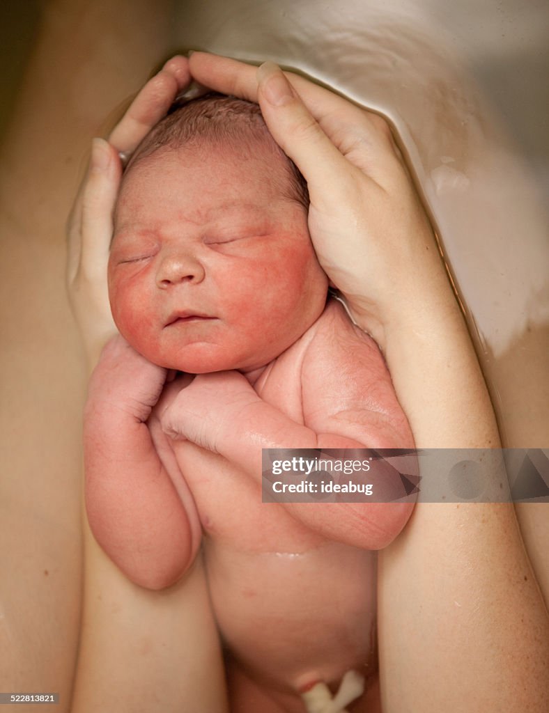 Le braccia della Mamma con neonato dopo il parto in acqua in casa