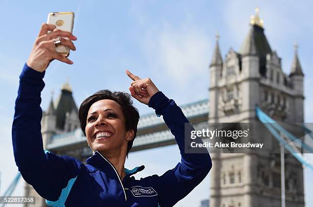 Dame Kelly Holmes poses for a selfi photograph in front of Tower Bridge as she attends a photocall ahead of the Virgin Money London Marathon at The...