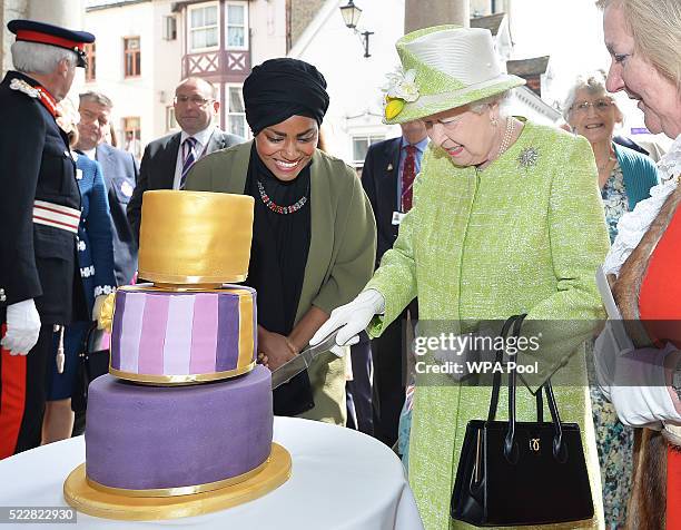 Queen Elizabeth II receives a birthday cake from Nadiya Hussain, winner of the Great British Bake Off, during her 90th Birthday Walkabout on April...