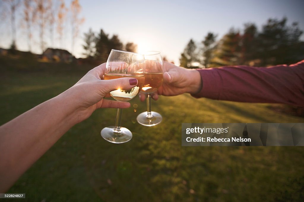 Man and woman clinking wine glasses at sunset