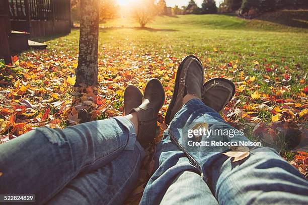 couple lying on leaf strewn grass - shoes man stock pictures, royalty-free photos & images