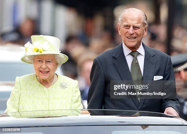 Queen Elizabeth II and Prince Philip, Duke of Edinburgh travel through Windsor in an open top Range Rover after her 90th Birthday Walkabout on April...