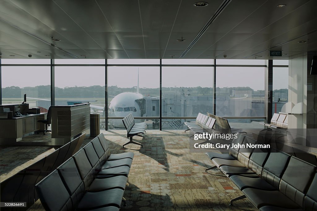 Empty airport lounge with plane outside.