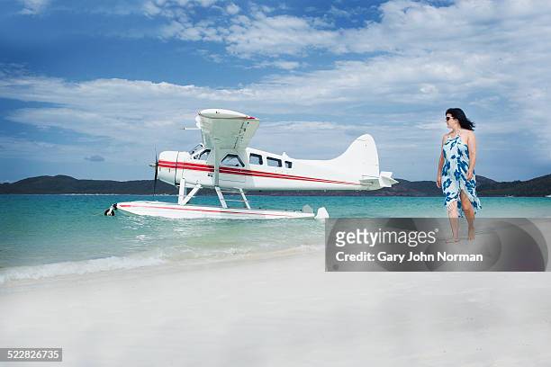 woman walks past seaplane on tropical beach. - hamilton island stockfoto's en -beelden