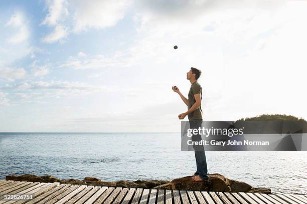 man juggling with balls while standing on a rock. - manly beach stock pictures, royalty-free photos & images