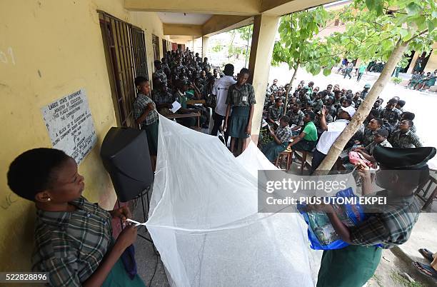 Students hold a treated mosquito net during a malaria prevention action at Ajah in Eti Osa East district of Lagos, on April 21, 2016. Dozens of...