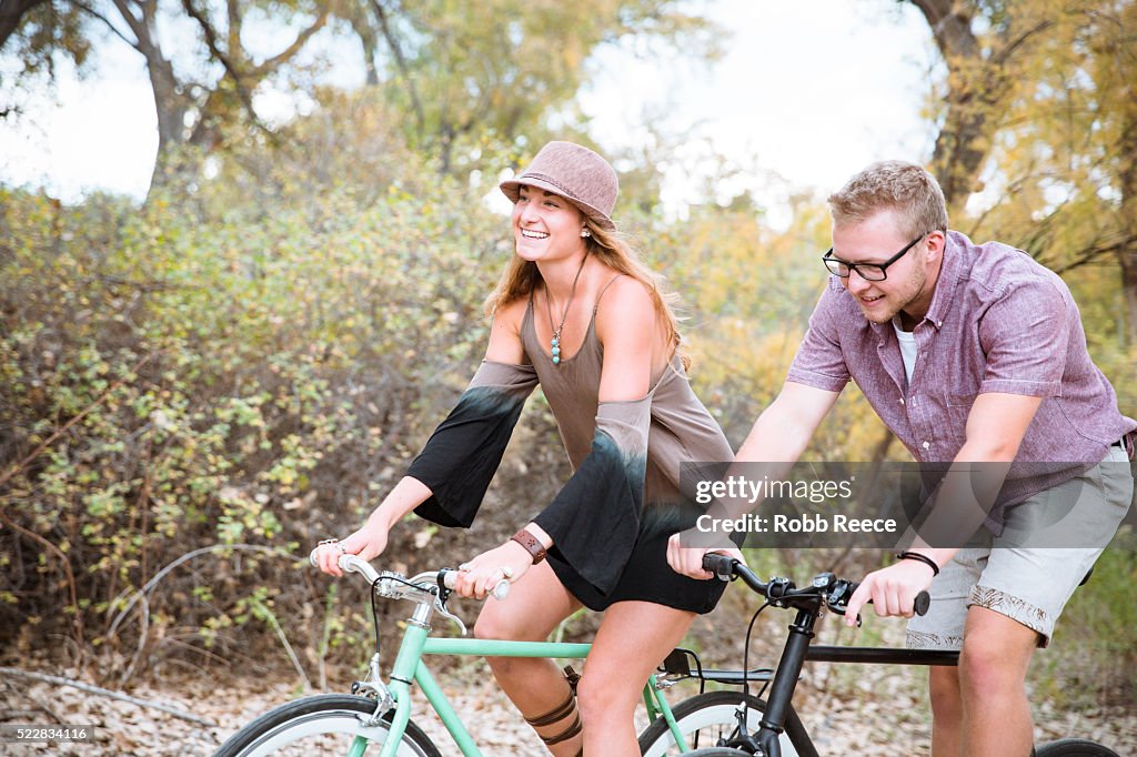 A young, happy man and woman riding bicycles in a park for fitness