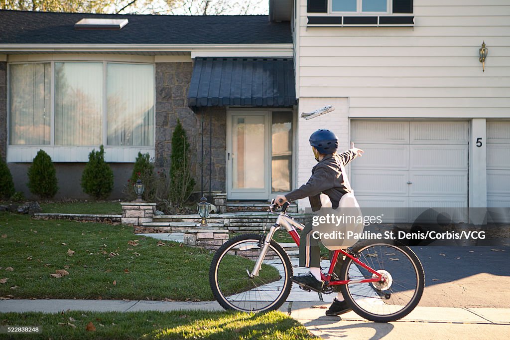 Boy delivering newspapers on his bicycle