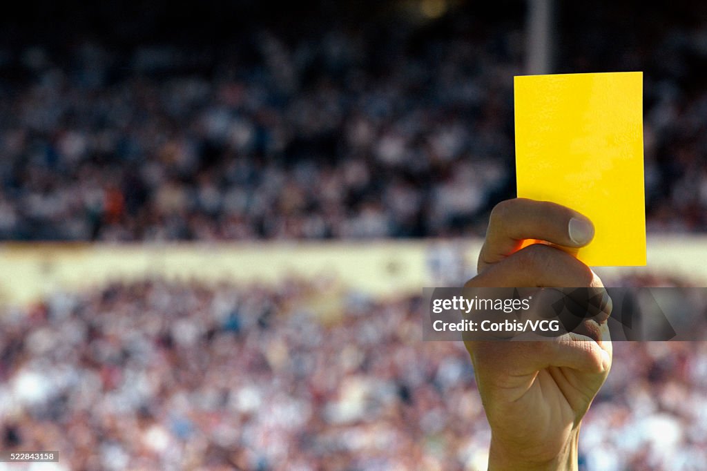 Hand holding up a yellow card