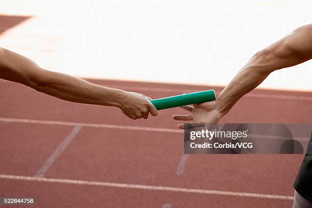 relay runners exchanging baton, close-up - relais athlétisme mains photos et images de collection