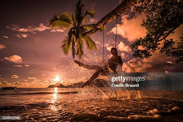 happy woman having fun on a swing above the sea. - sunset beach stockfoto's en -beelden