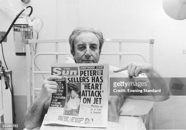 British actor Peter Sellers points to a headline in 'The Sun' which speculates about his current period of hospitalisation, 21st March 1977. The...