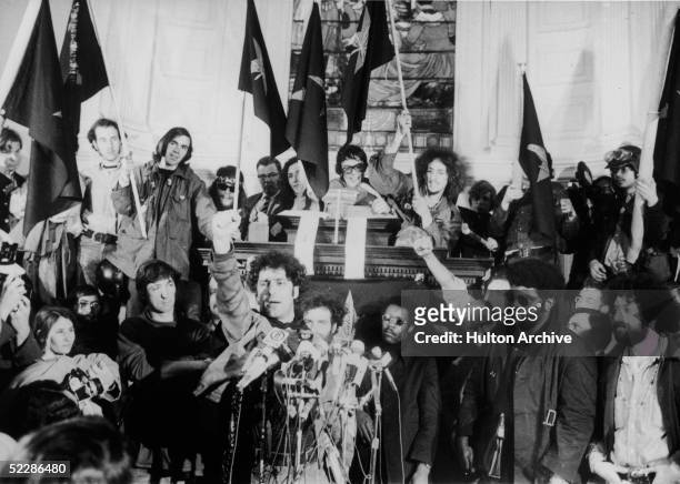 American political activist Abbott "Abbie" Hoffman raises a fist from behind a bank of microphones during an unidentified rally in New York, late...