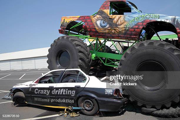 monstertruck crushing car - monster trucks stock pictures, royalty-free photos & images