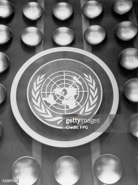 The emblem of the United Nations, depicting a map of the world encircled by the olive wreath of peace, circa 1950. Dating from 1946, the logo...