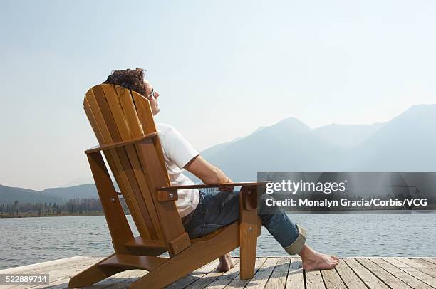 man naps by the lake - adirondack chair stockfoto's en -beelden