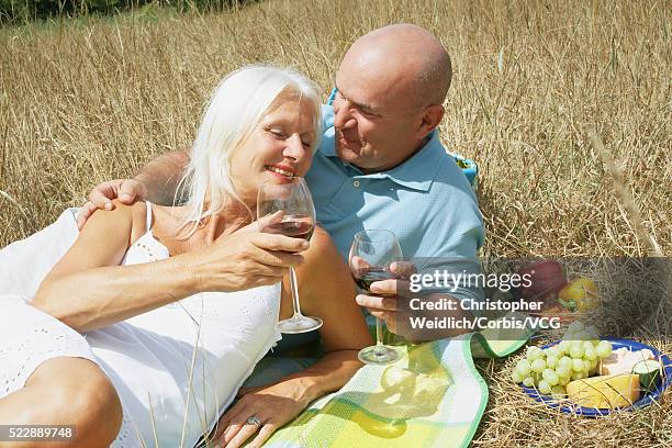 happy couple drinking wine on a picnic banket - banket stock-fotos und bilder