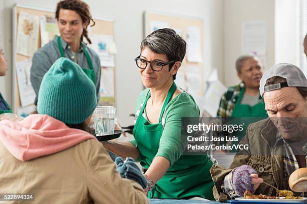 volunteers attending homeless people in soup kitchen - philanthrop stock-fotos und bilder