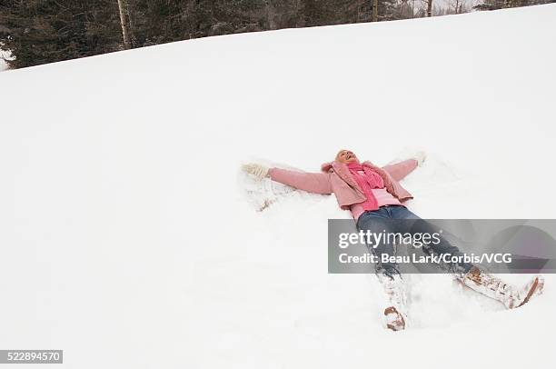 woman making snow angel - snow angel stock pictures, royalty-free photos & images