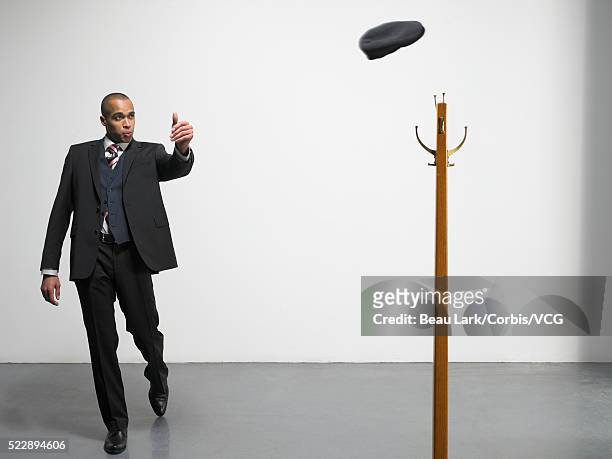 businessman throwing hat onto coat rack - suit rack stock pictures, royalty-free photos & images