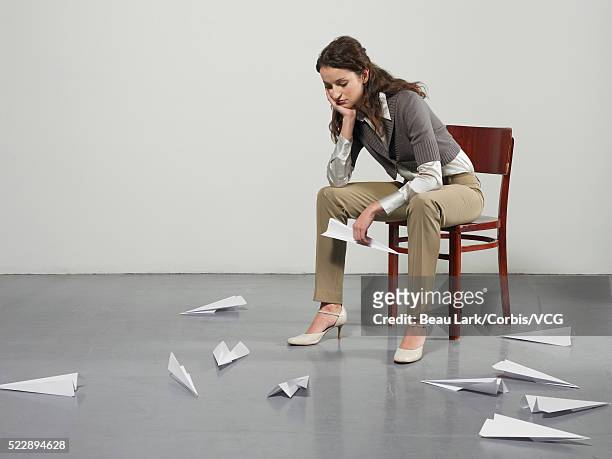 bored businesswoman with paper airplanes - mala postura fotografías e imágenes de stock