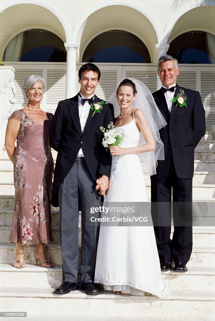 Bride and groom with their parents on stairs at wedding