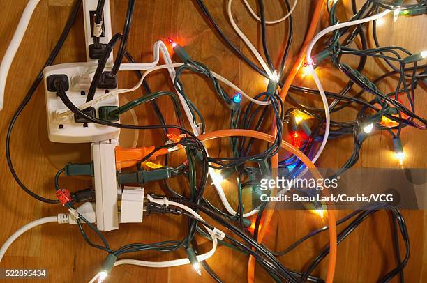 tangled christmas lights and electrical cords on hardwood floor - christmas stress stock pictures, royalty-free photos & images