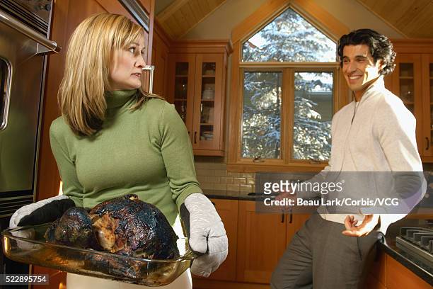 man laughing at woman holding burnt turkey - funny turkey images stockfoto's en -beelden