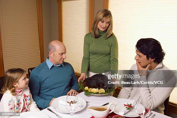 woman serving burnt turkey to family - awkward dinner imagens e fotografias de stock