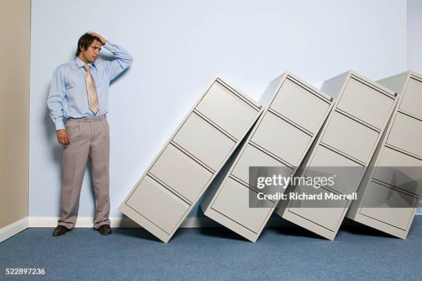businessman looking at fallen file cabinets - funny mistake stock pictures, royalty-free photos & images